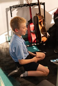 Josh smiling with guitars behind